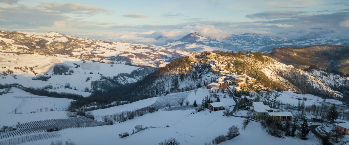 Un village enneigé, niché dans une vallée, avec des montagnes en toile de fond.