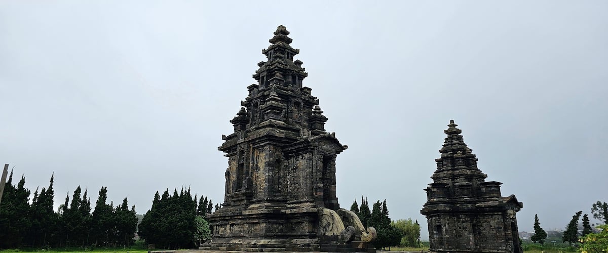Ancient stone structures with intricate carvings, surrounded by a gravel path and wooden railings.