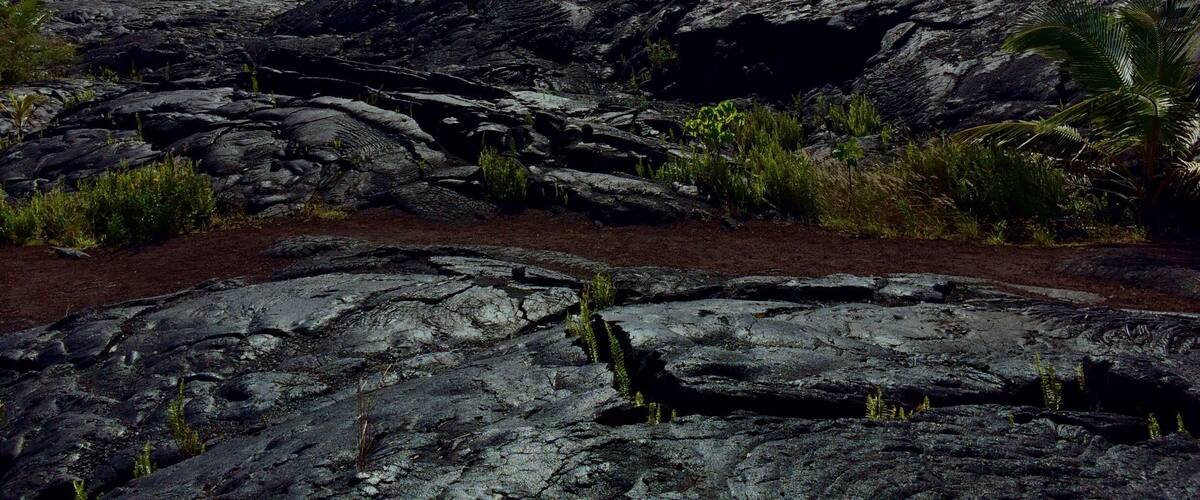 A volcanic landscape with rugged terrain and sparse vegetation.