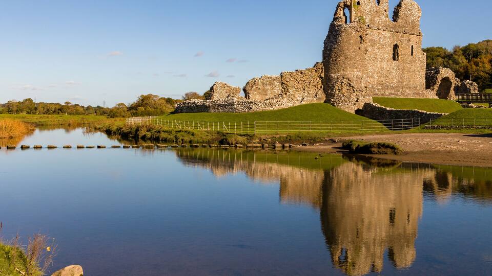 A historic castle with a moat and reflection in the water.