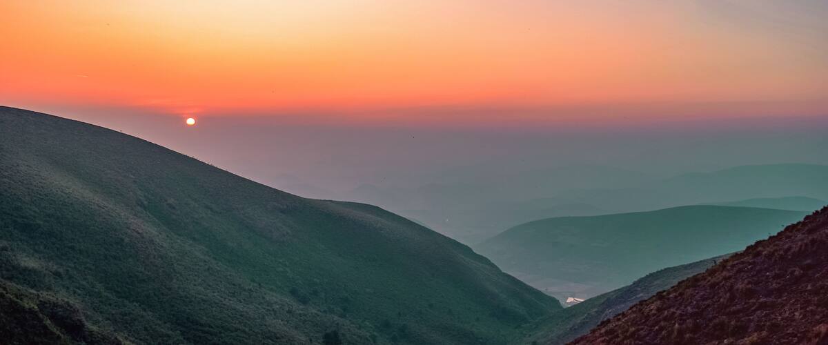 A sunrise over a valley with rolling hills.