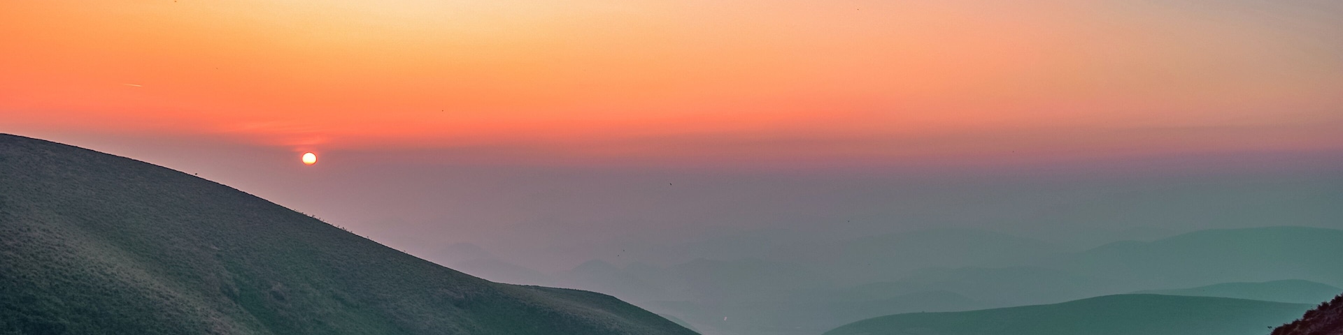 A sunrise over a valley with rolling hills.