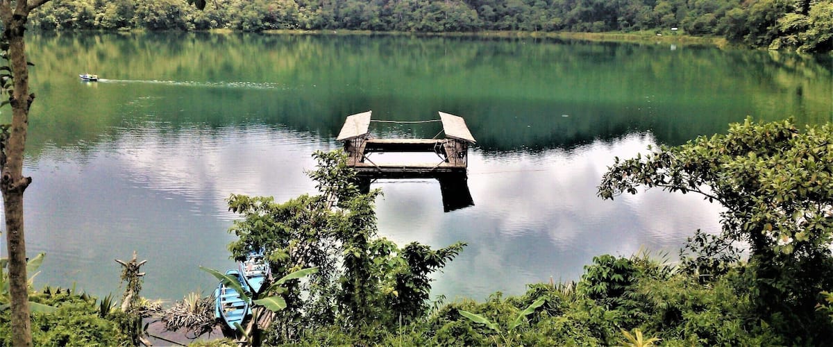 A calm lake with a wooden dock and a small boat.