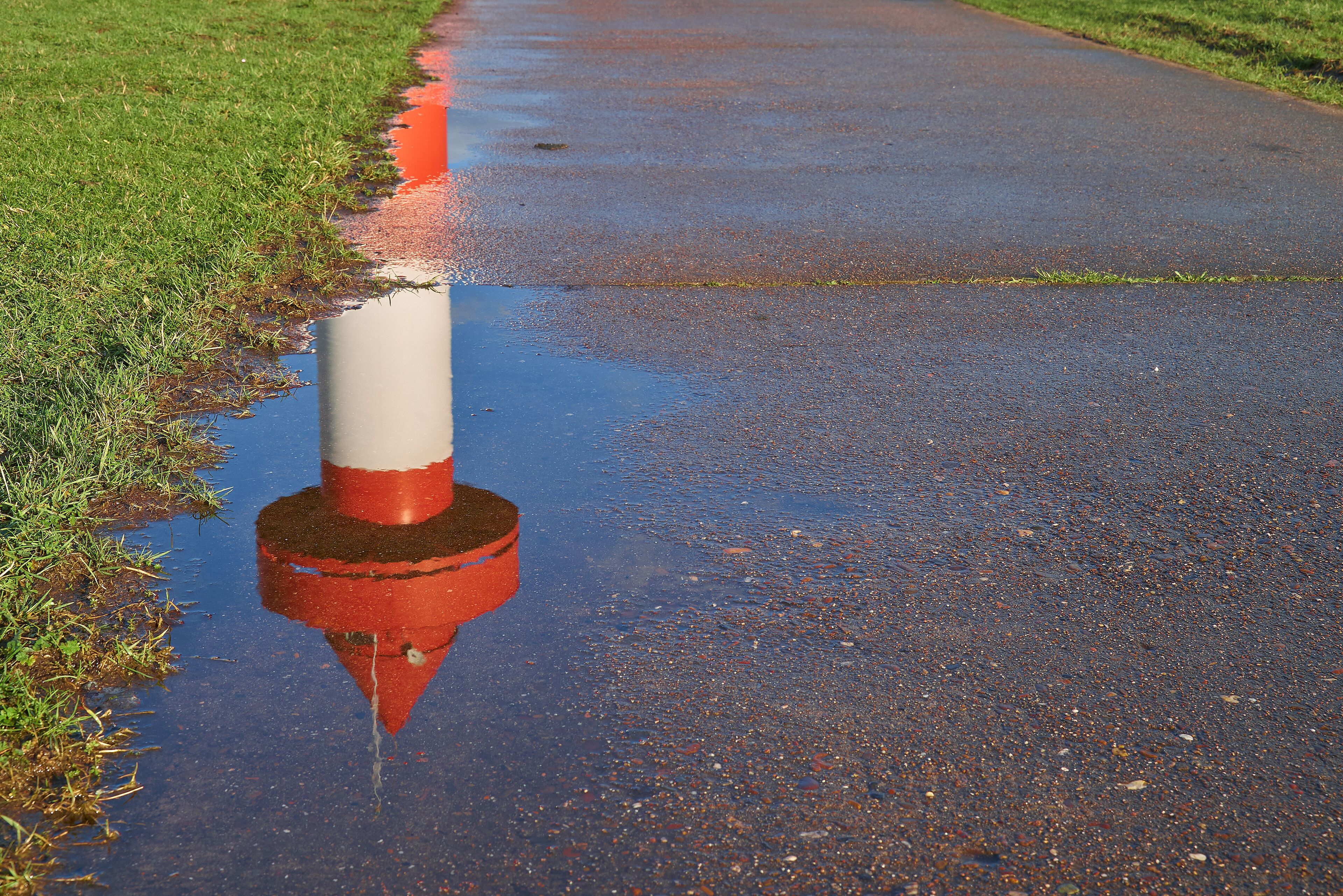 top of small lighthouse at Ritzenbütteler Sand, municipality Lemwerder (district Wesermarsch, Germany) on a sunny spring day with blue sky reflecting in a puddle on a footpath