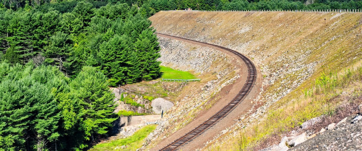 A railway track curving through a forested hillside.
