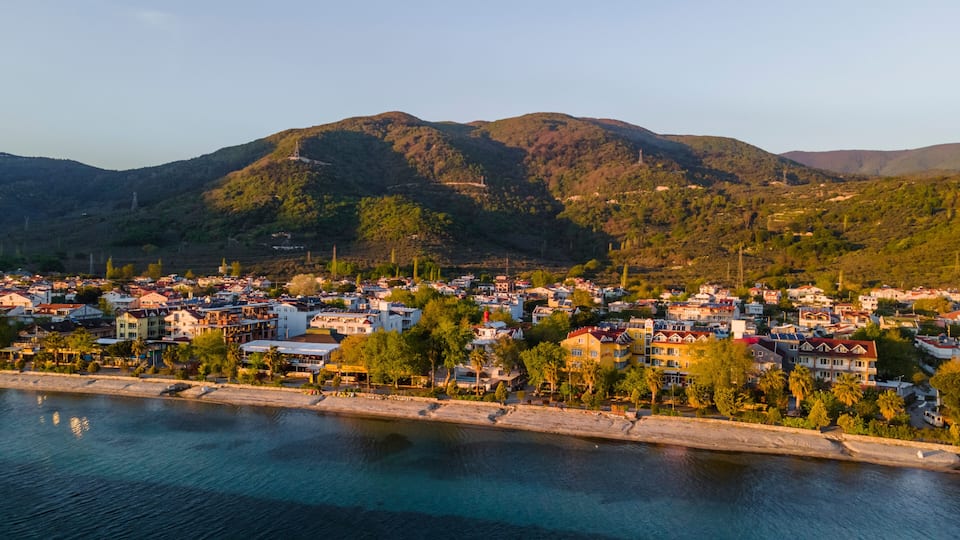 A coastal town with buildings along the waterfront, surrounded by hills and mountains.