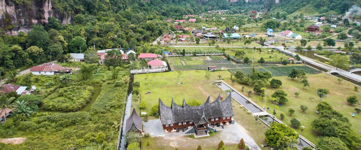 A village nestled in a valley with steep cliffs, surrounded by lush greenery and traditional houses.