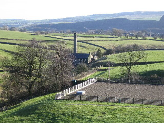Chimney at Embsay Beck. From the dam at Embsay Reservoir. The chimney is at the old mill by Crown Cottage Farm. The fenced area in the foreground appears to be an underground water storage tank.