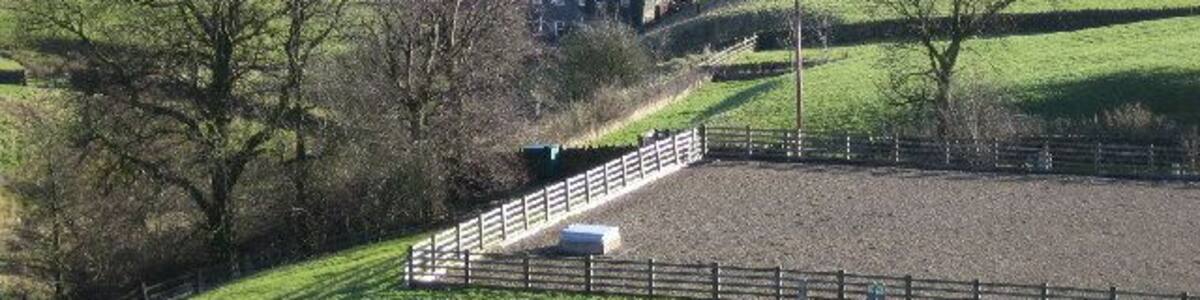 Chimney at Embsay Beck. From the dam at Embsay Reservoir. The chimney is at the old mill by Crown Cottage Farm. The fenced area in the foreground appears to be an underground water storage tank.