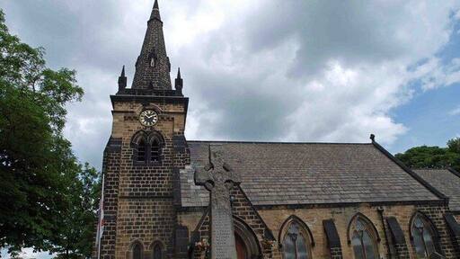 St Paul's parish church, Brierley, South Yorkshire, seen from the southwest. The stone cross in the foreground is the parish war memorial.
