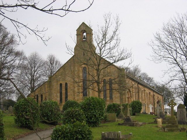 A historic church with a tall bell tower, surrounded by a cemetery with headstones.