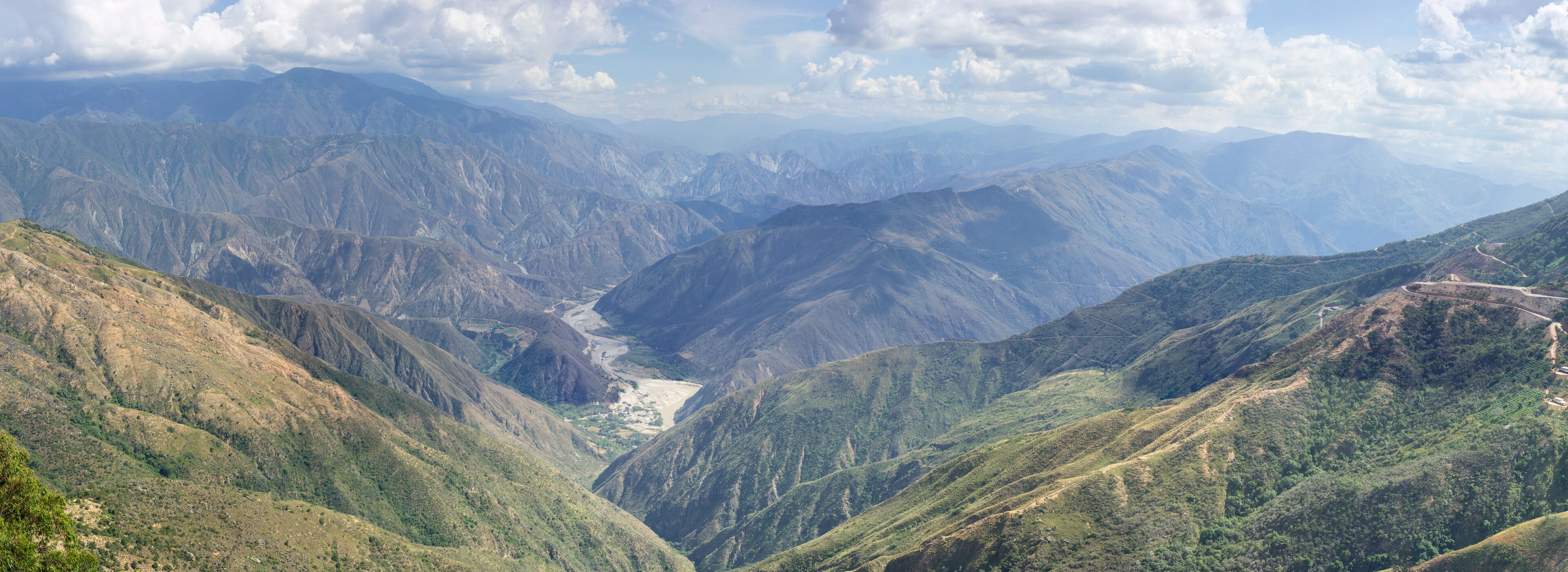 A mountainous landscape with a valley and winding roads.
