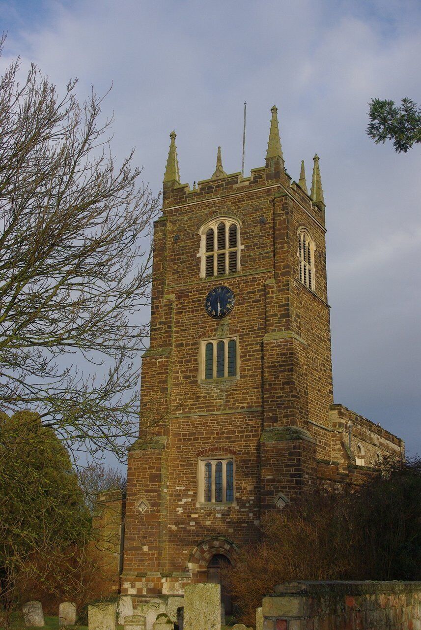 A historic brick tower with a clock, pointed spires, and arched windows.