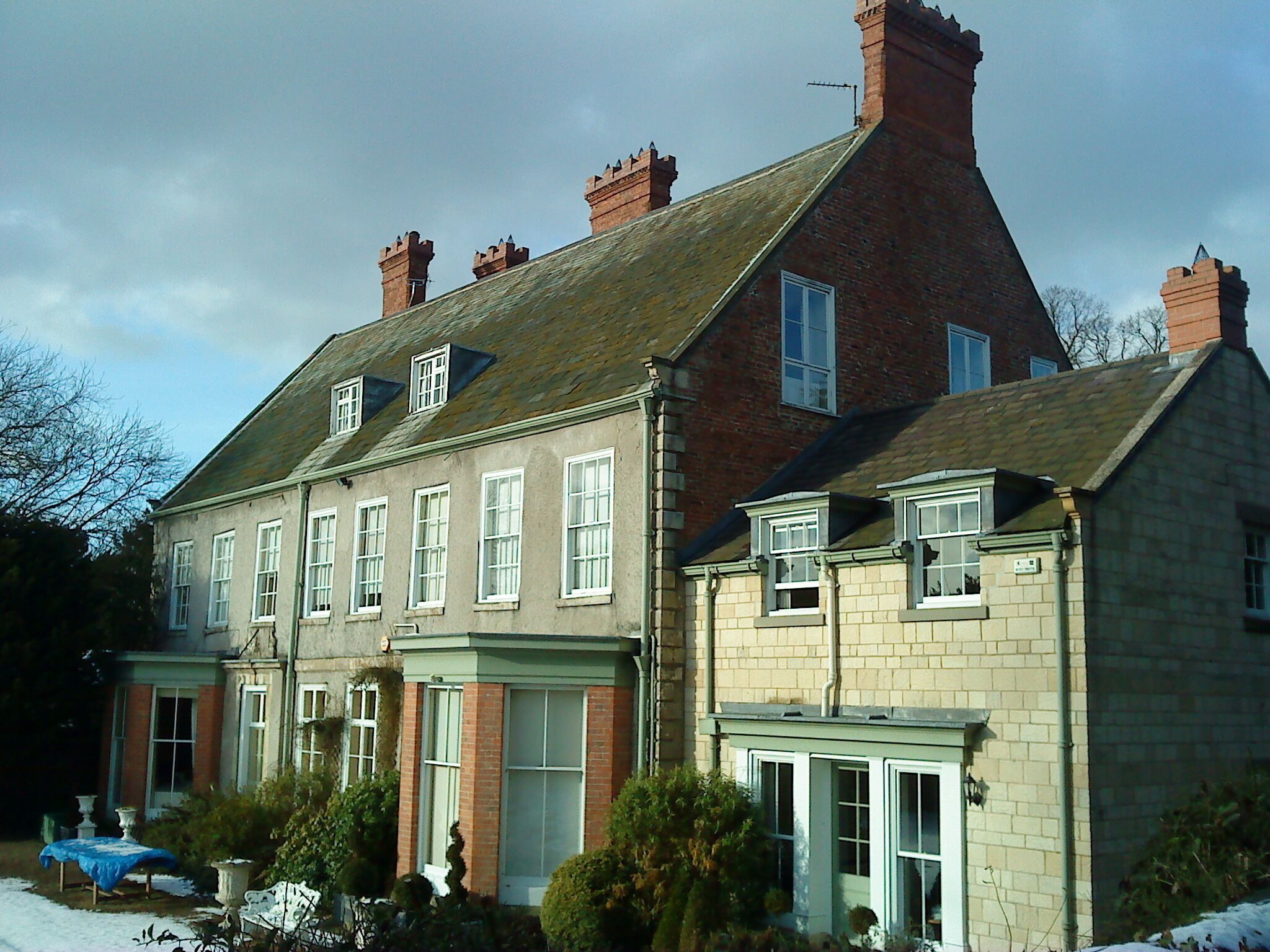 A large, historic building with multiple chimneys and a steeply pitched roof.