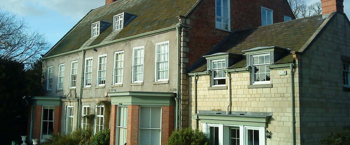 A large, historic building with multiple chimneys and a steeply pitched roof.