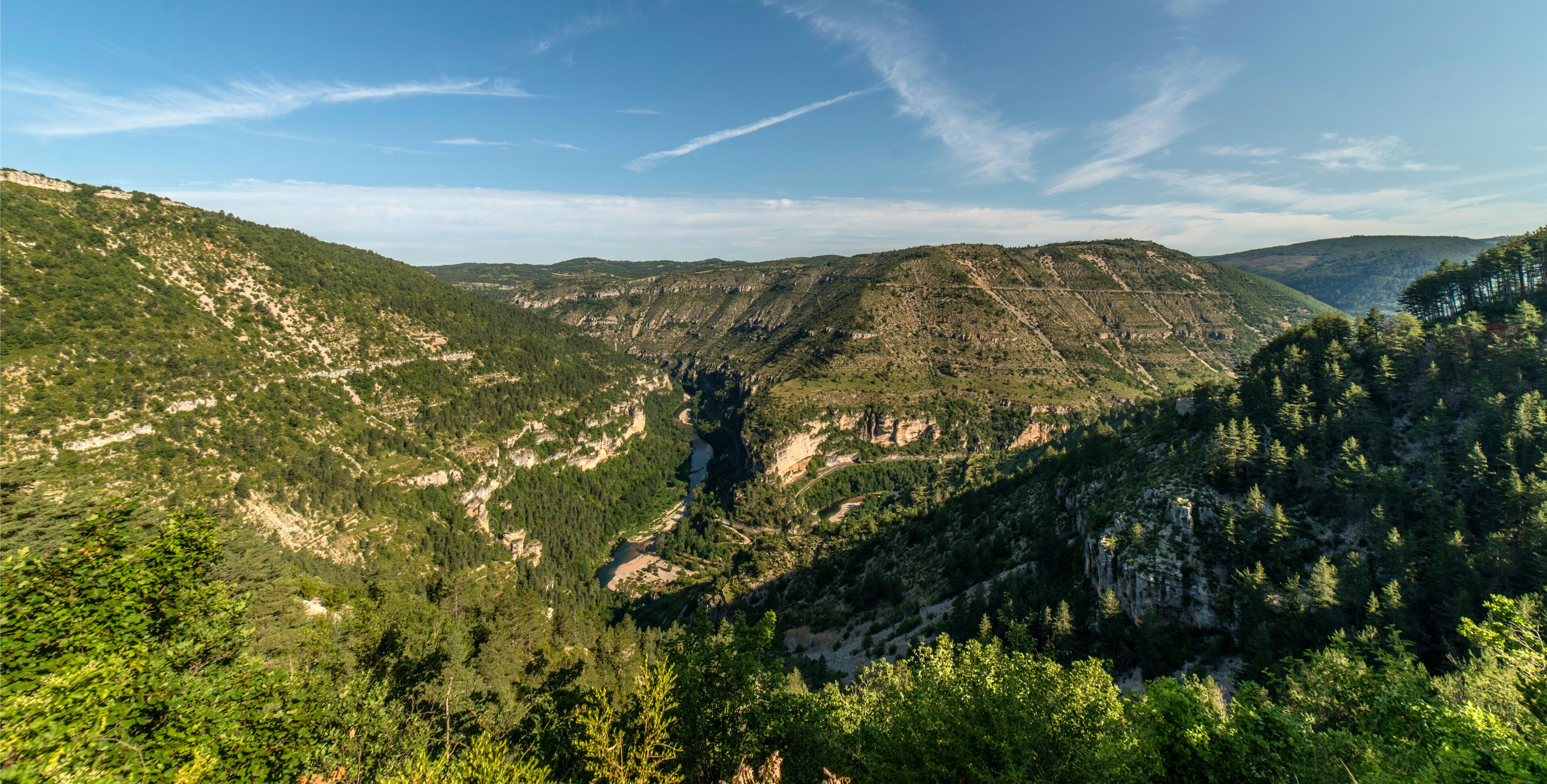A mountainous landscape with dense forests and a river valley.