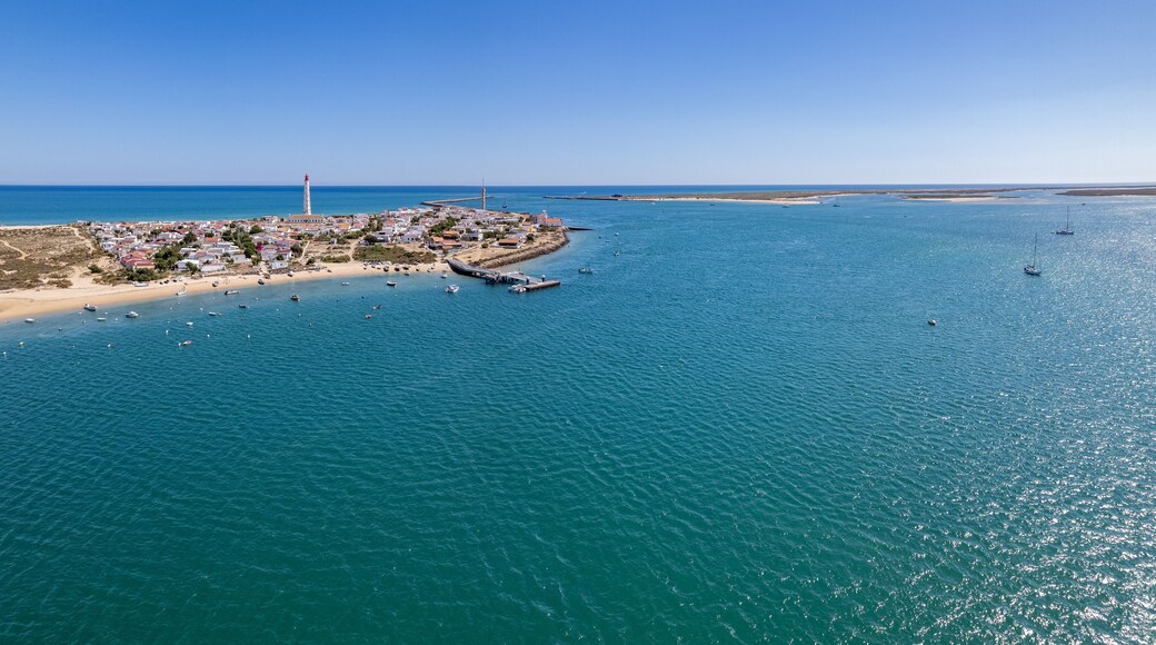 Aerial seascape view of Cape Santa Maria lighthouse island, Praia do Farol beach, one of the barrier islands that protect the Ria Formosa natural park, in Algarve Tourism Destination region, Portugal