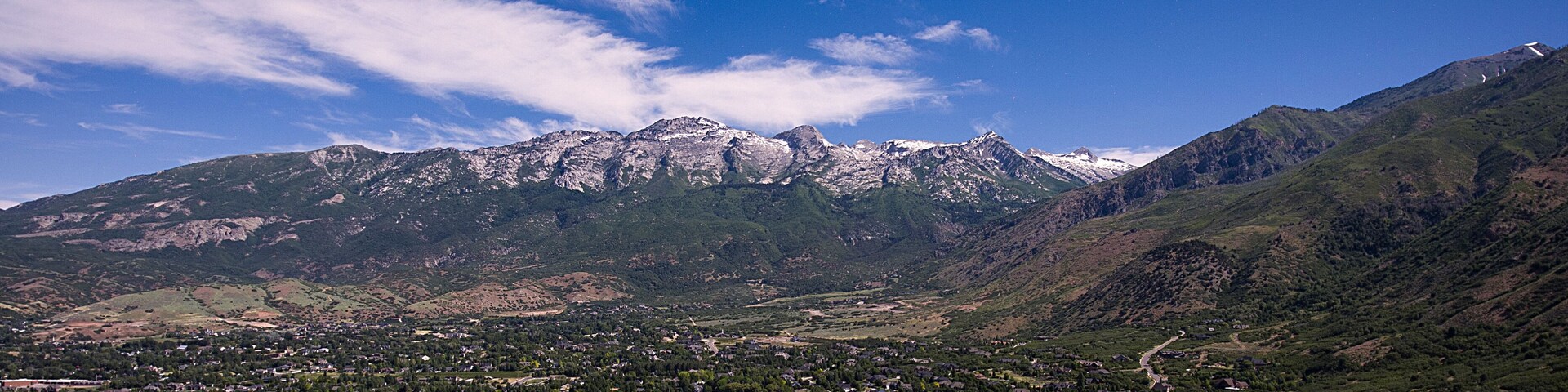 An aerial drone shot captures Lone Peak Mountain and Alpine Utah on a sunny summer day.