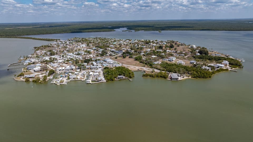 An aerial view of a coastal town with houses, docks, and a marina.