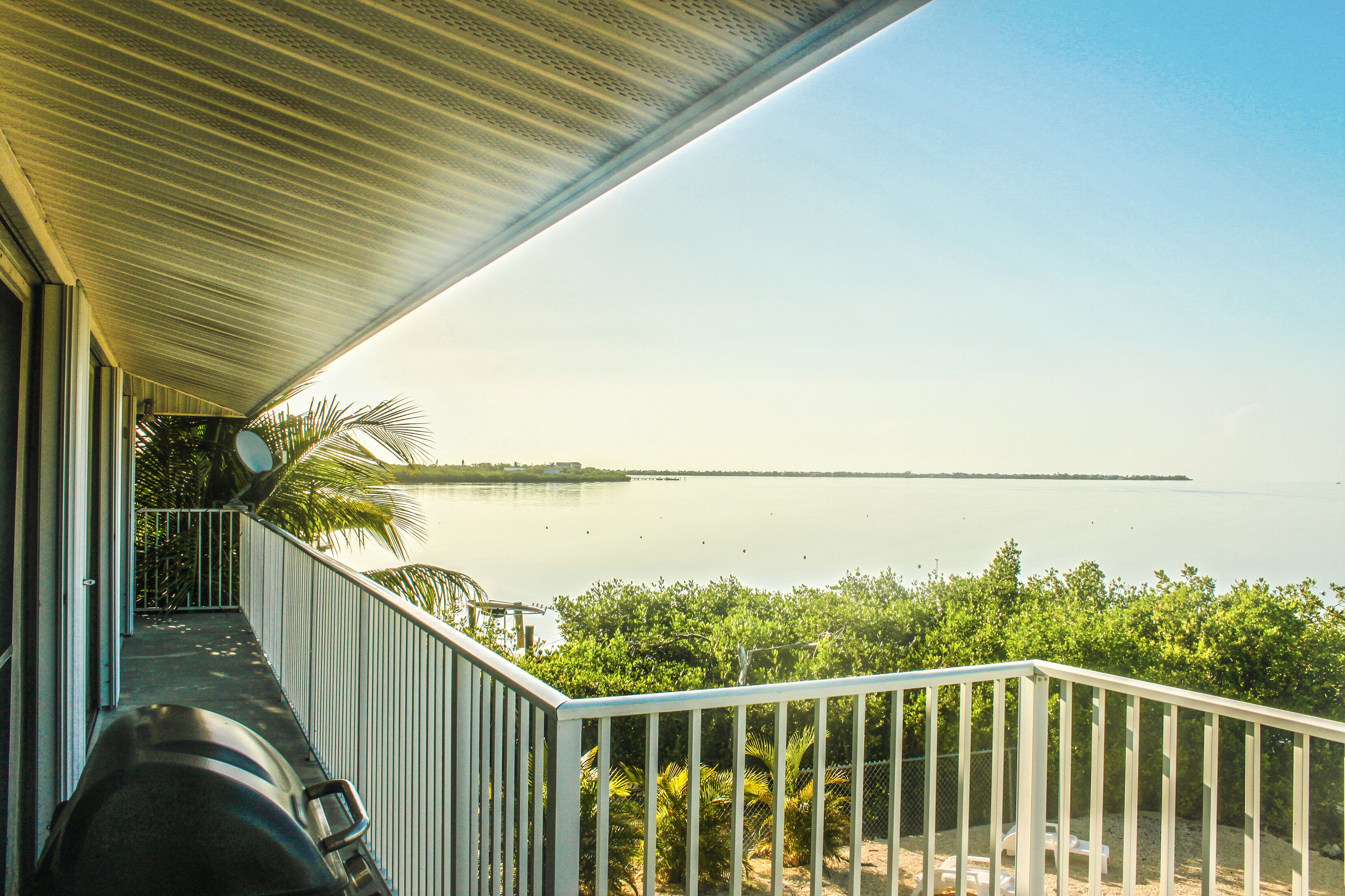 Looking out over tropical  ocean from balcony of vacation rental over private beach with grill and TV satellite - Horizon is thin line