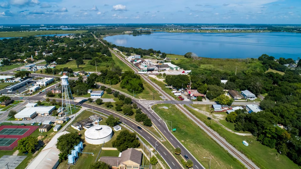 An aerial view of a town with a large lake, roads, and industrial buildings.