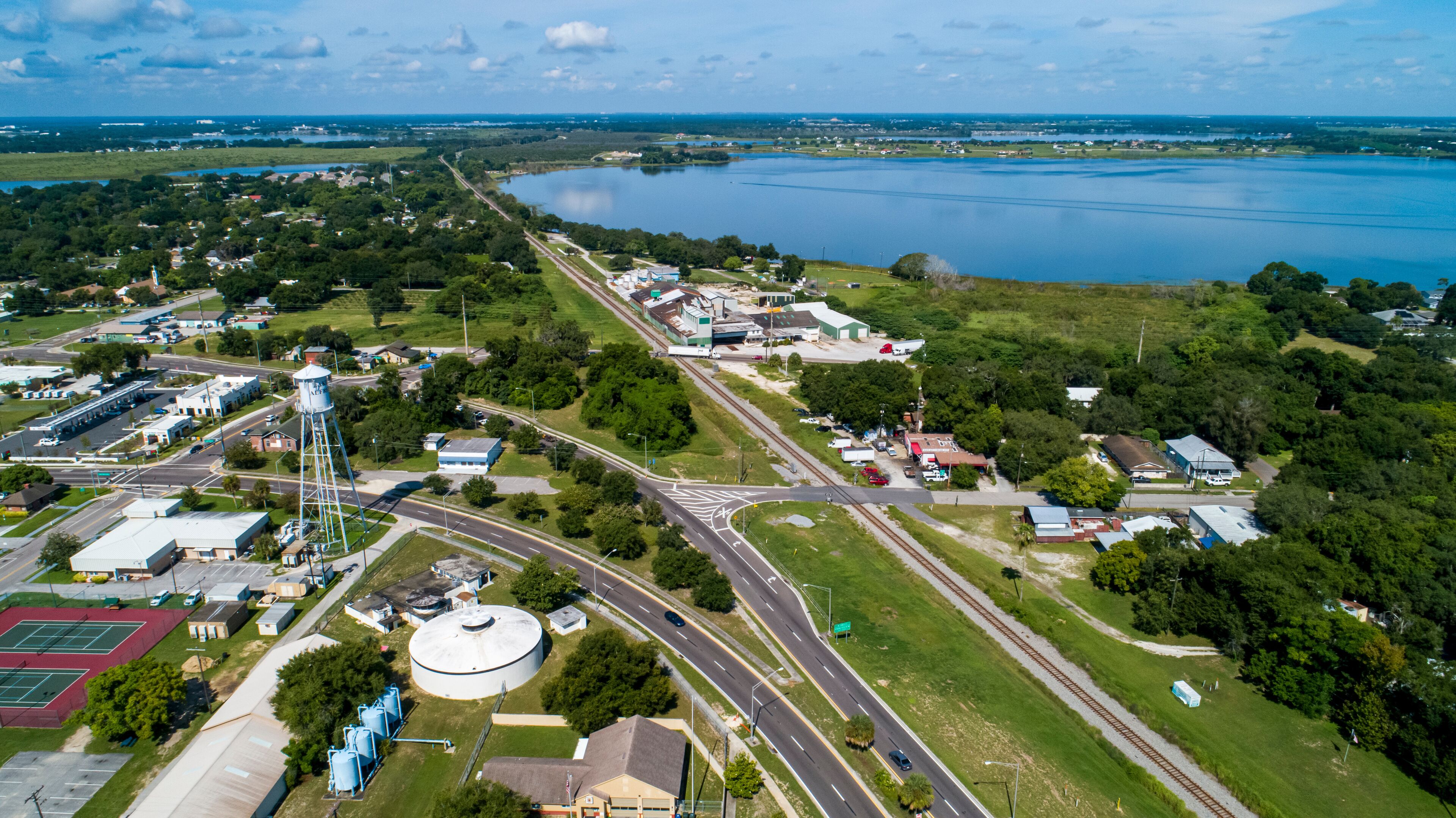 An aerial view of a town with a large lake, roads, and industrial buildings.