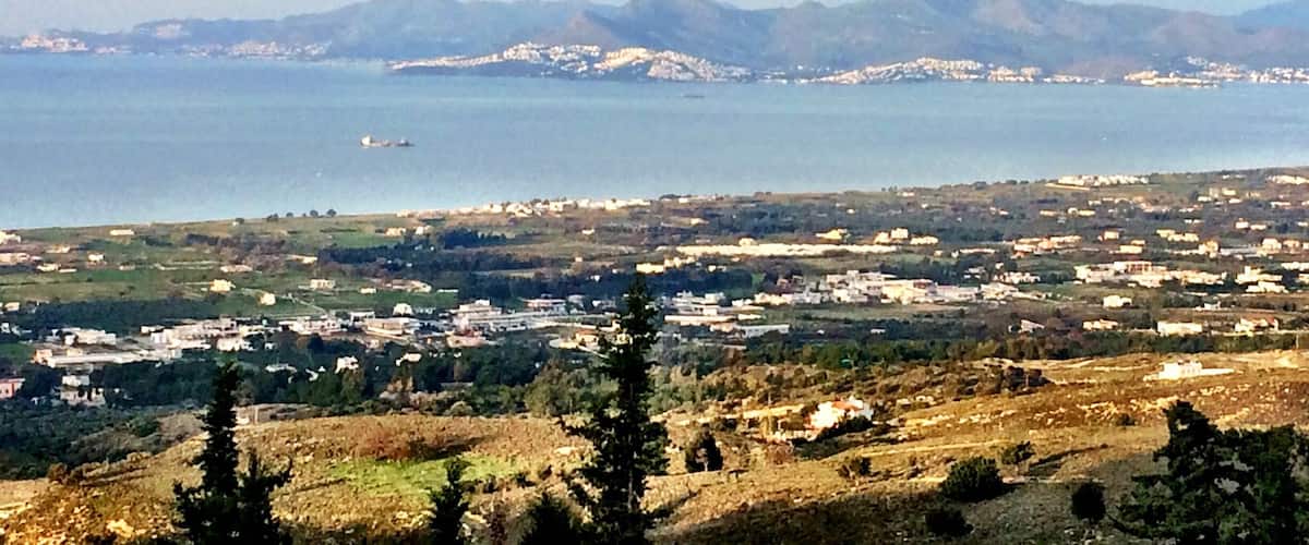A coastal town with a view of the sea and mountains in the background.