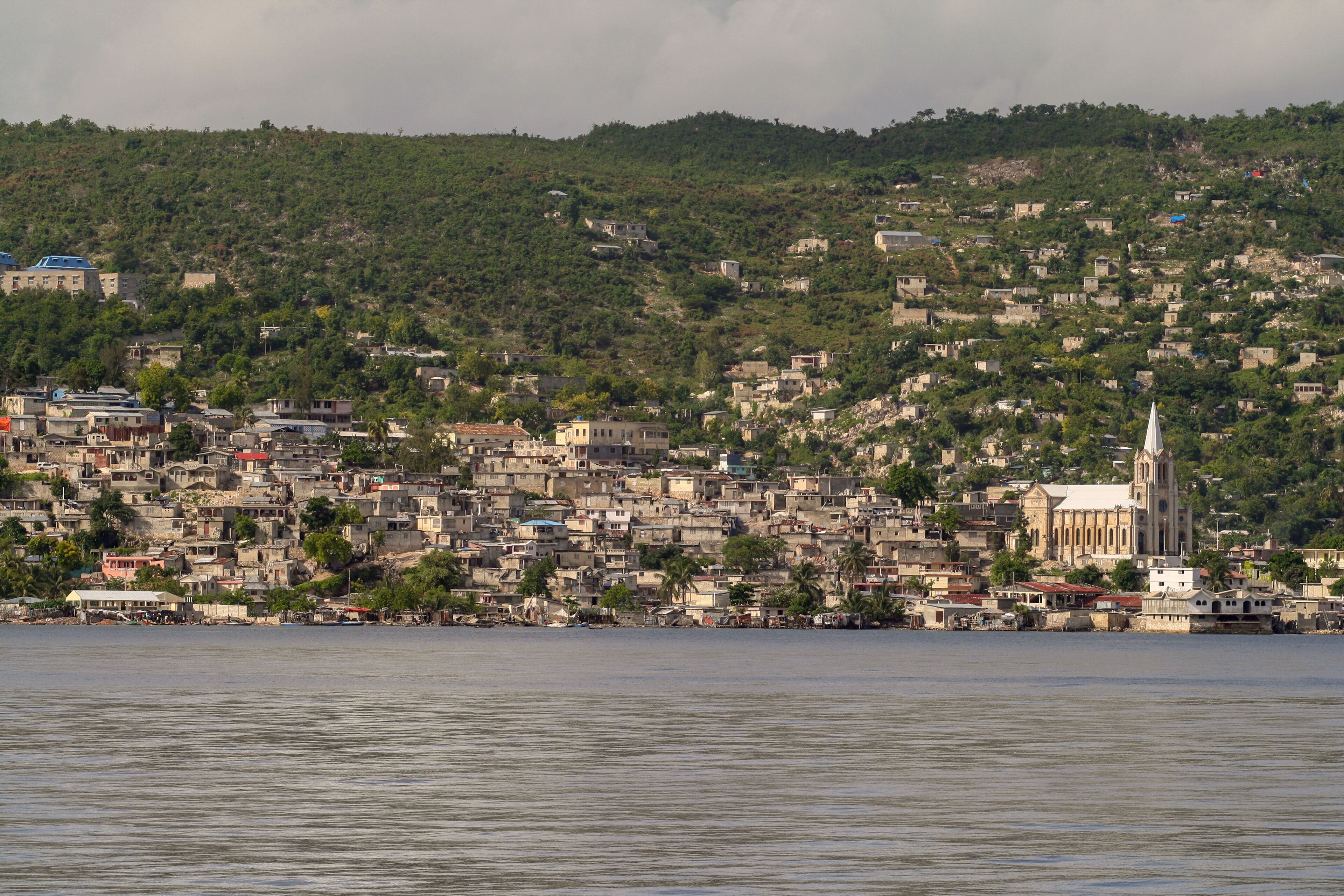 A coastal cityscape with dense housing and a prominent church on a hill.