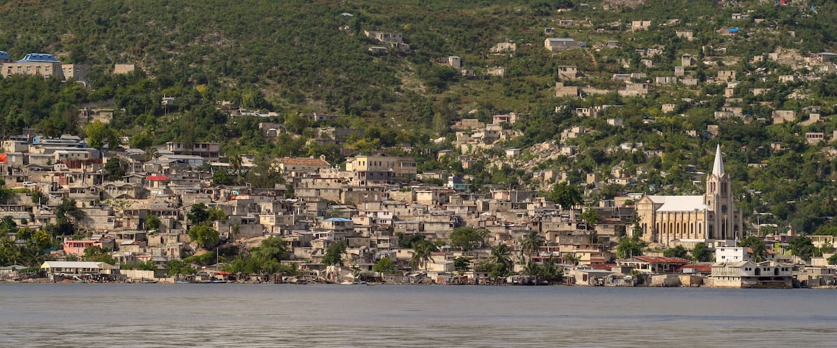 A coastal cityscape with dense housing and a prominent church on a hill.