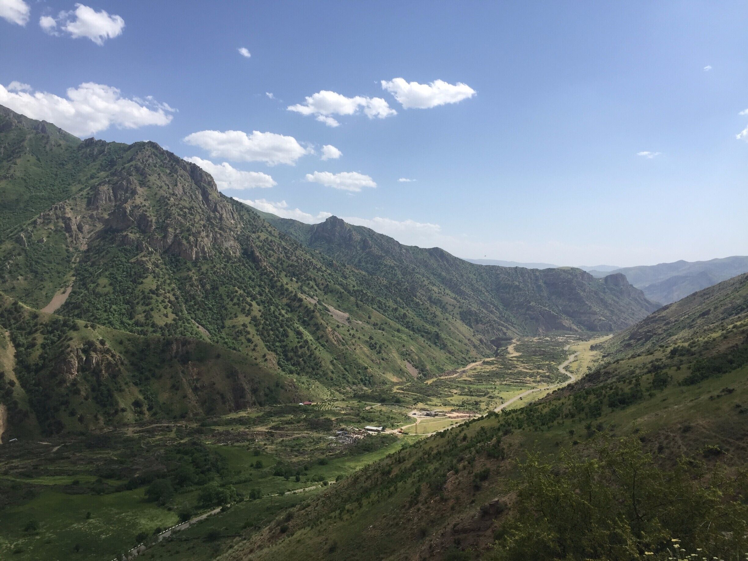 A mountainous landscape with a valley, a river, and scattered buildings.