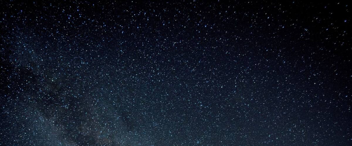 A starry night sky over a field with a visible Milky Way.