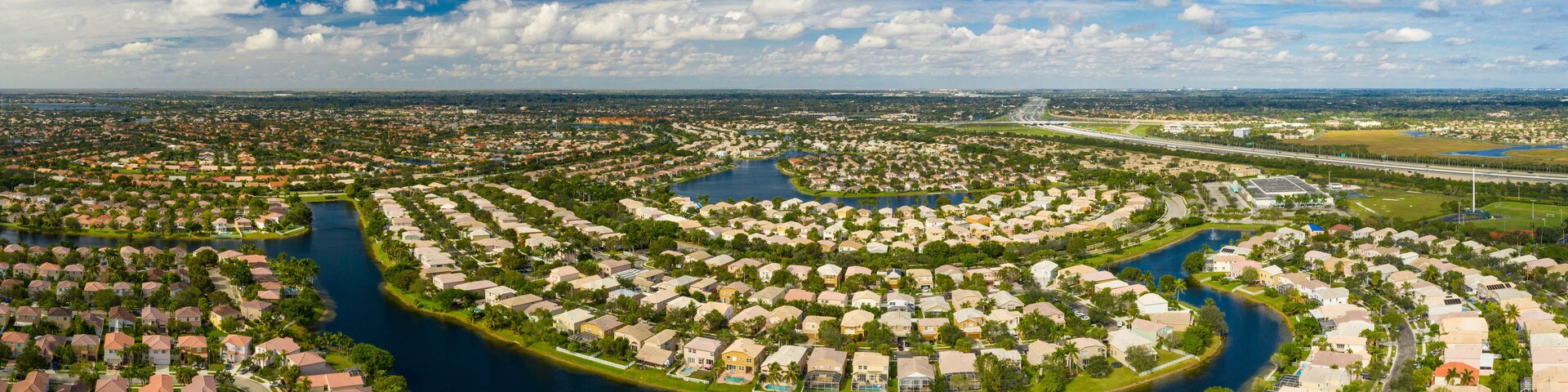 A residential area with a river meandering through it, surrounded by houses and greenery.