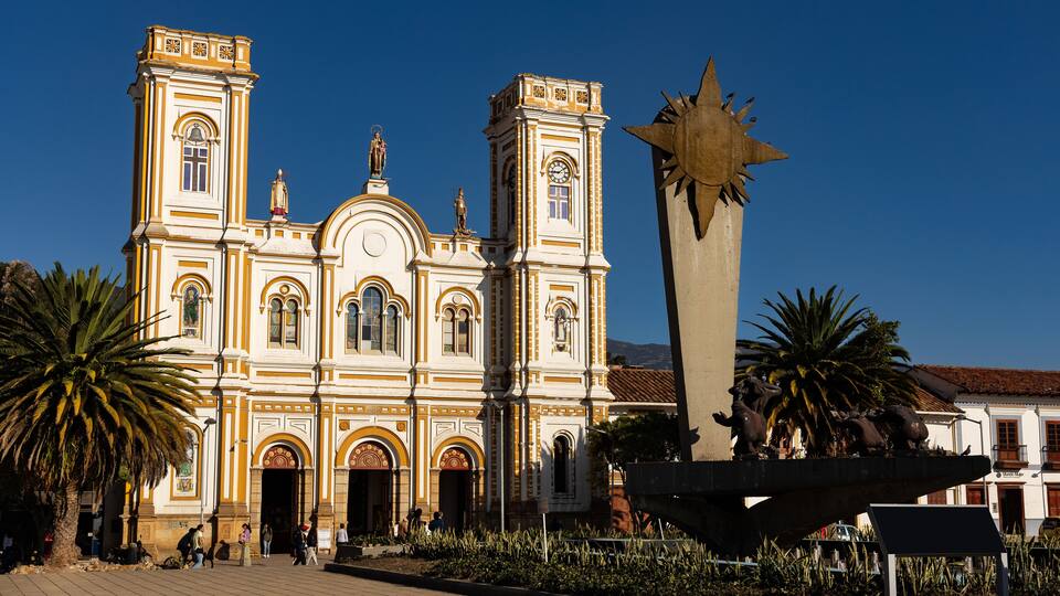 A historic church with two towers and a large sun sculpture in front.
