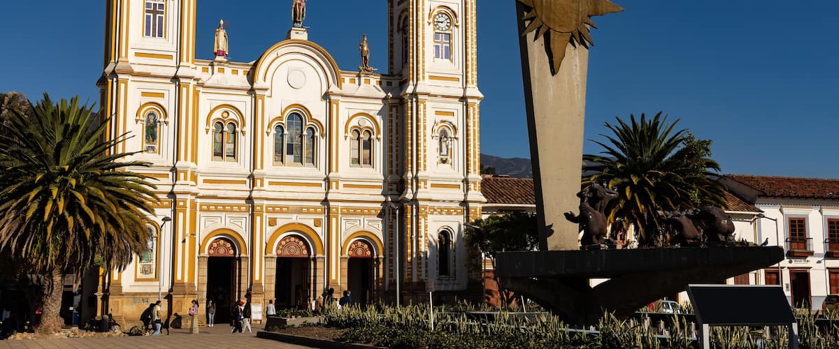 A historic church with two towers and a large sun sculpture in front.