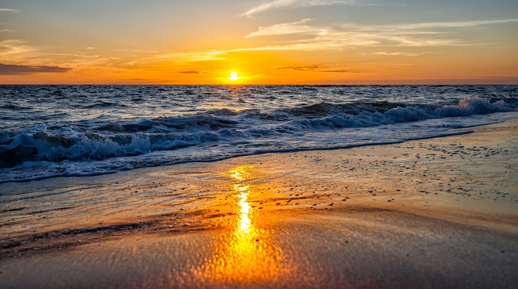 Una playa con olas al atardecer.