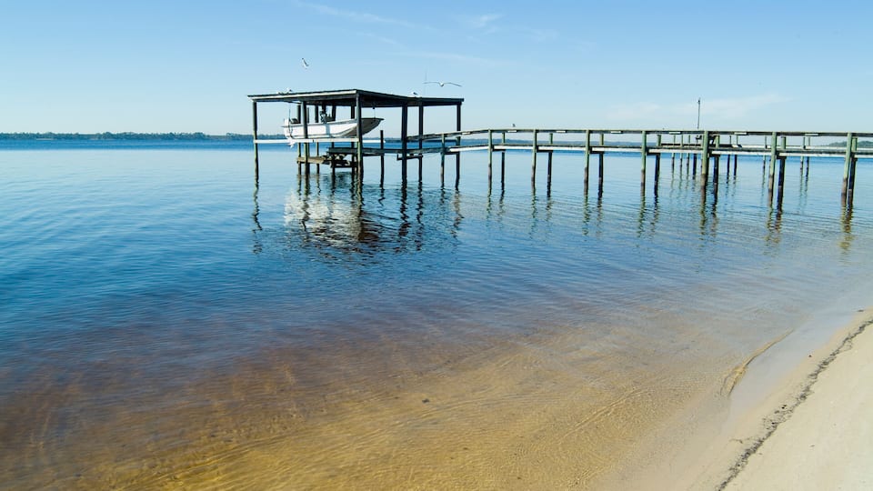 A pier extending into calm waters with a small boat docked at the end.