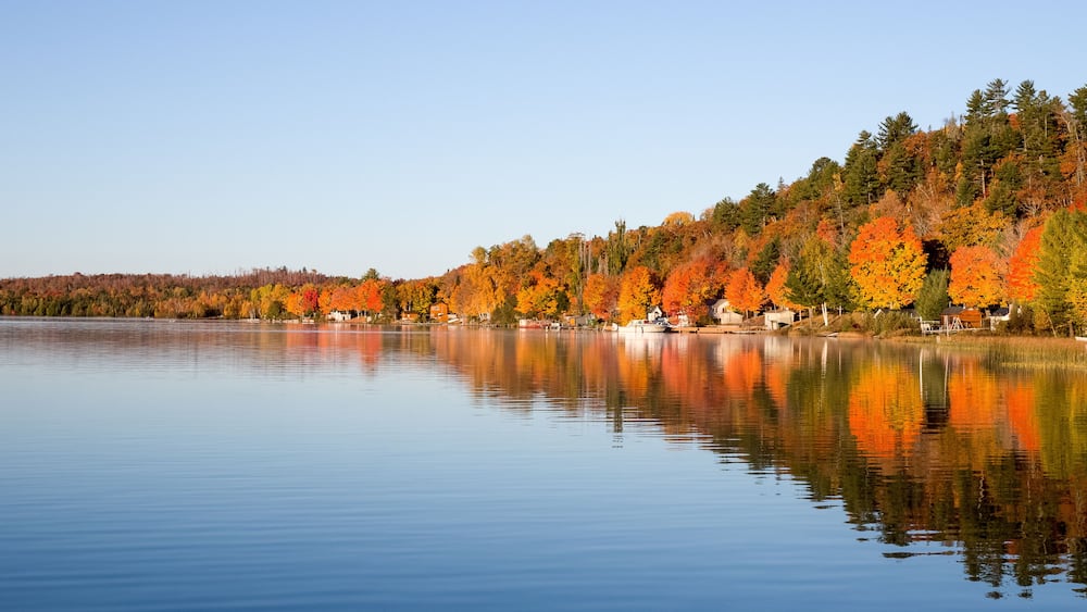 A calm lake with autumn-colored trees reflecting on the water.