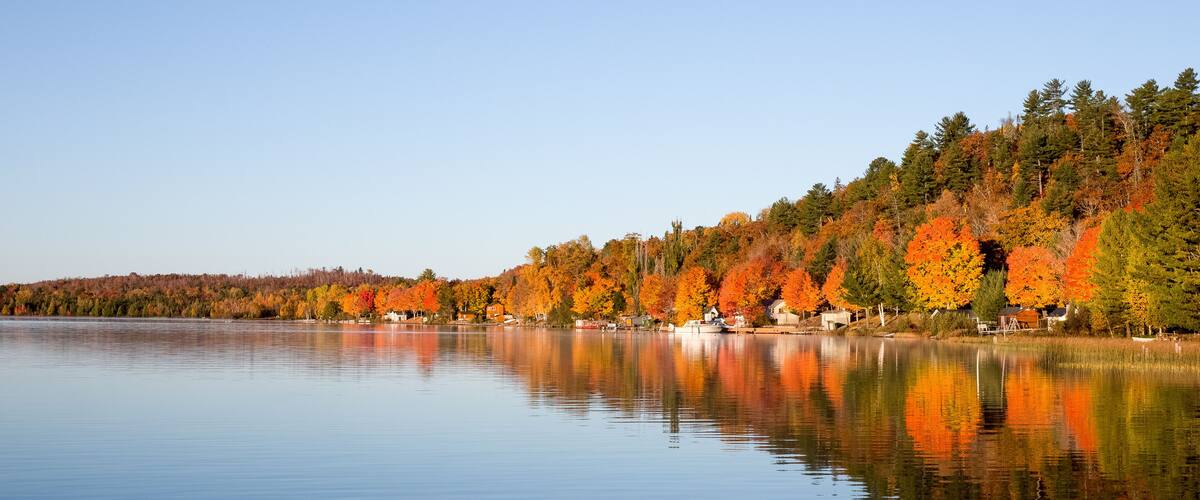 A calm lake with autumn-colored trees reflecting on the water.