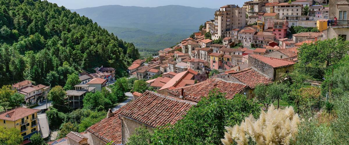 A hillside town with terracotta-roofed buildings nestled among lush green hills.