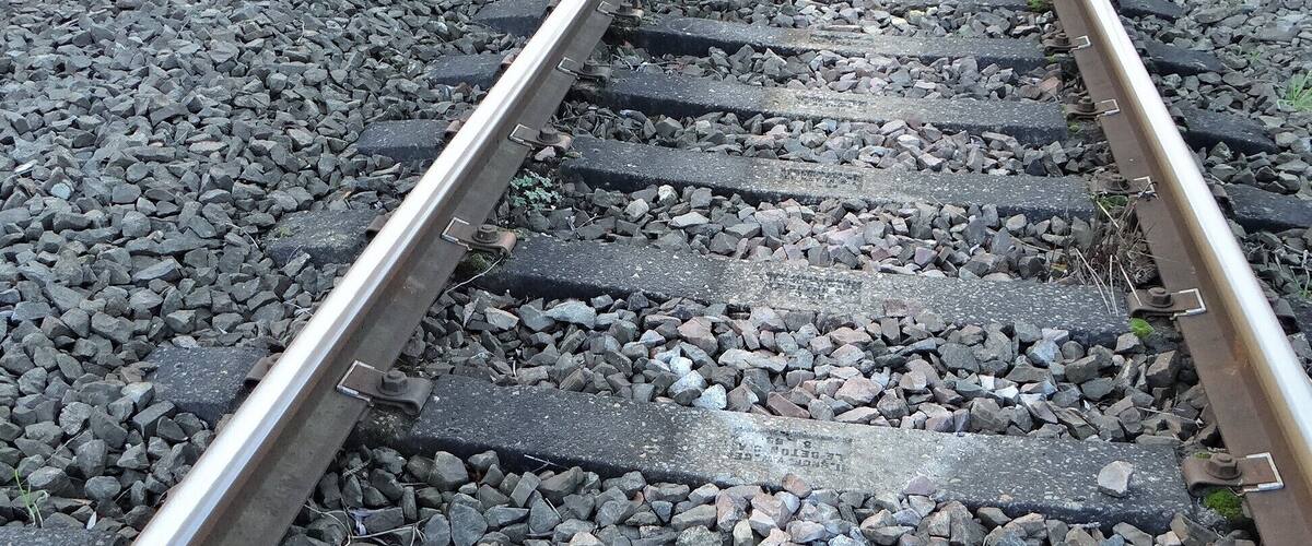 Railway tracks with gravel and vegetation on the sides.