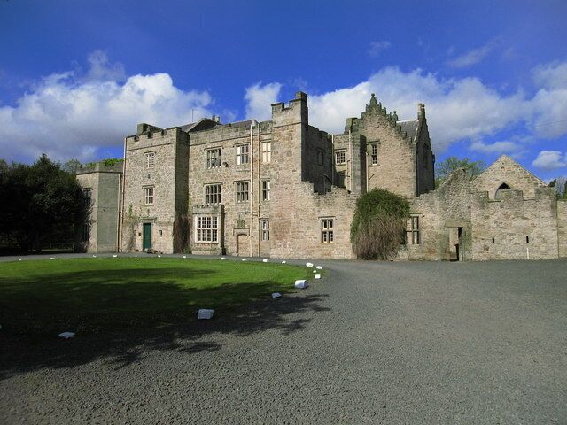 A historic stone castle with a large lawn in front.