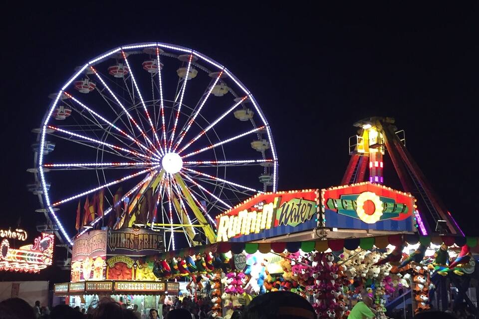 A Ferris wheel and a carnival ride at night.