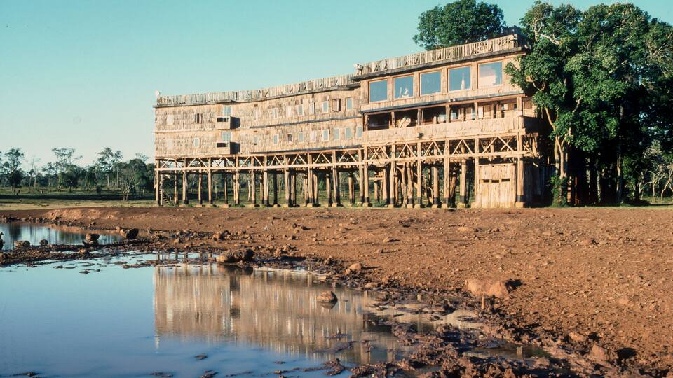 A wooden structure with a reflective water surface in front.