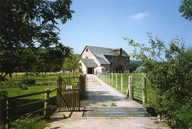 A stone building with a metal gate and a wooden fence leading to it.