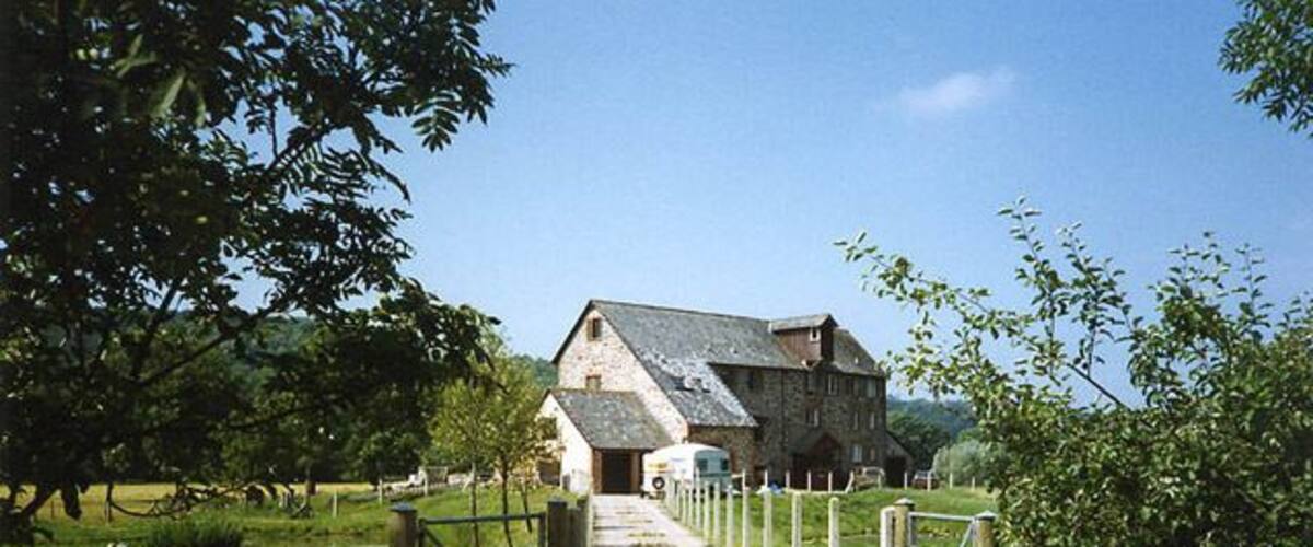 A stone building with a metal gate and a wooden fence leading to it.
