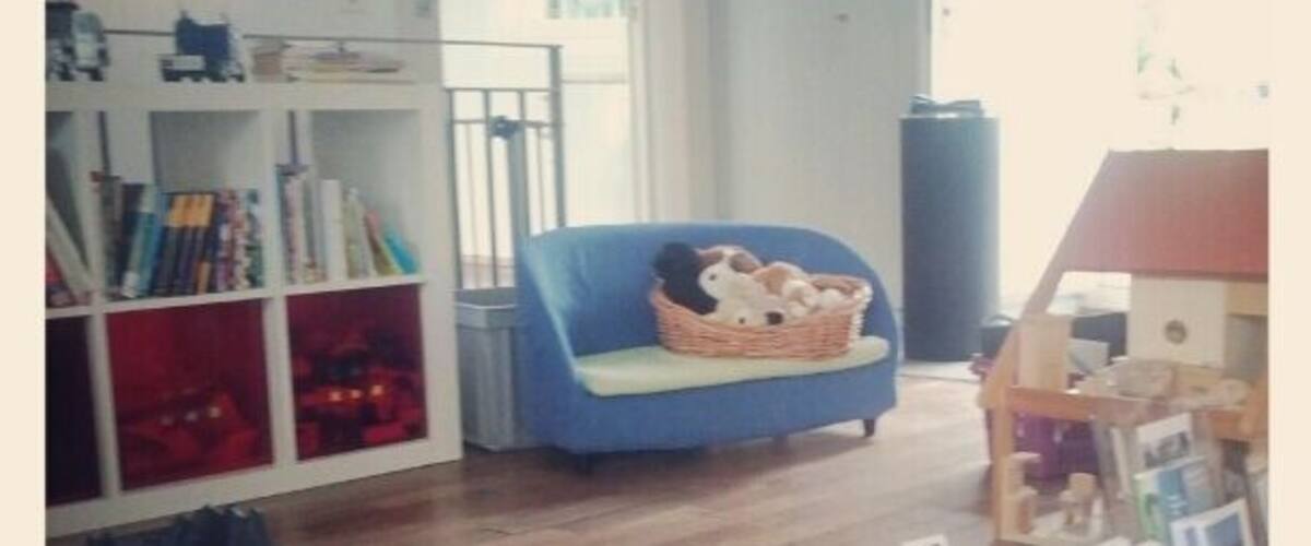 A cozy room with a blue sofa, a bookshelf, and a mat with books.