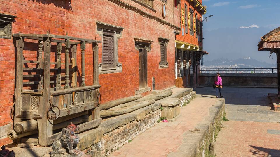 A traditional red brick building with wooden railings and a stone lion statue in front.