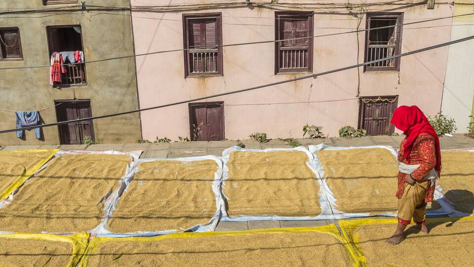 A person walking past a building with multiple windows and drying clothes on a line.