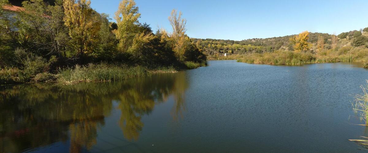 A calm river surrounded by trees and hills.