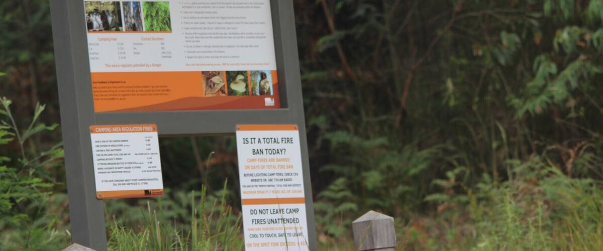 A signboard with information about Murrindindi Scenic Reserve, including camping fees and regulations.